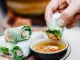Hand dipping Vietnamese spring roll in sauce