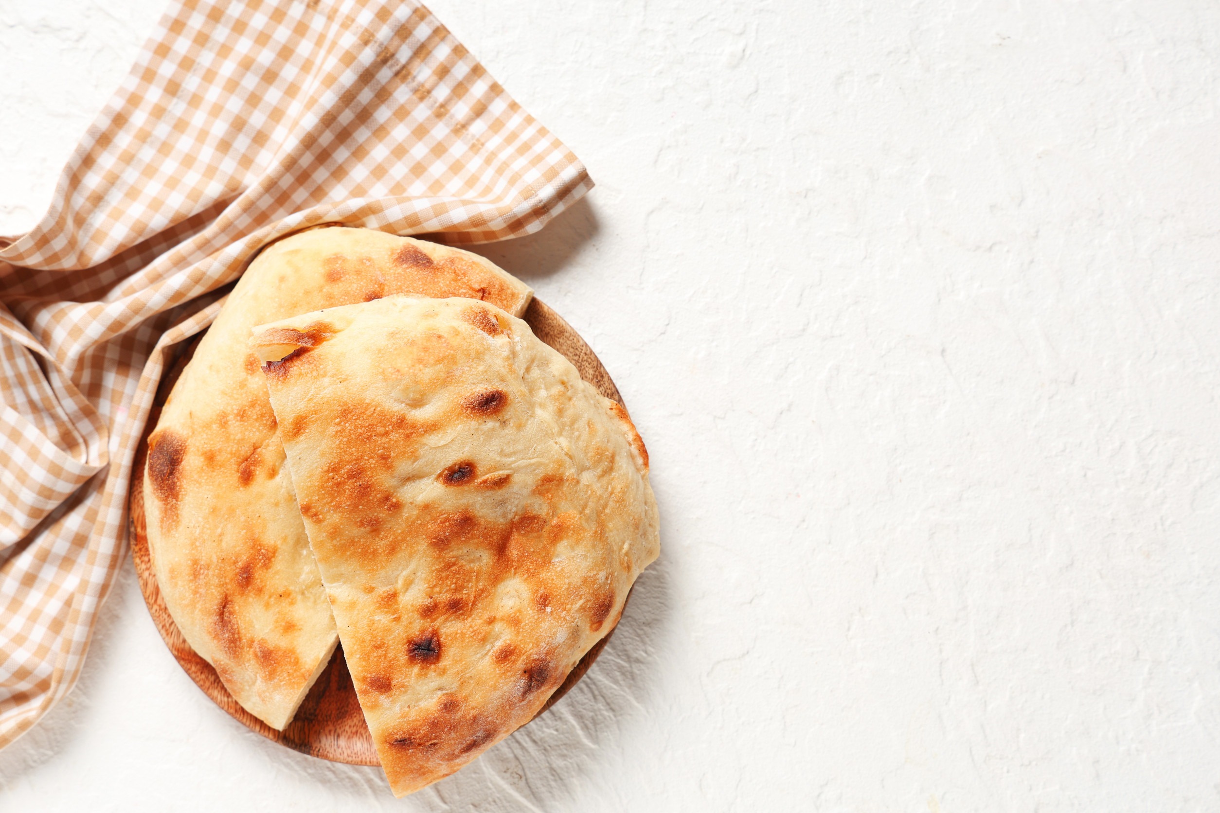 Wooden plate with pieces of tasty lavash on white background