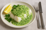cod in parsley sauce, lemon wedge, sprigs of parsley, knife and fork