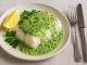 cod in parsley sauce, lemon wedge, sprigs of parsley, knife and fork