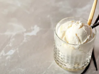 Glass with tasty vanilla ice cream on light background. Vanilla ice cream