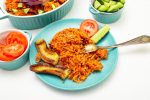 jollof rice on alight blue plate with banana, plantain strips