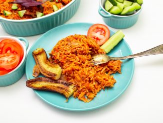 jollof rice on alight blue plate with banana, plantain strips