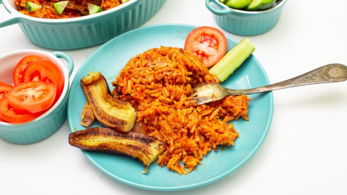 jollof rice on alight blue plate with banana, plantain strips