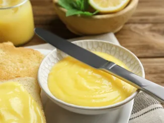 Delicious lemon curd and fresh toasts on wooden table, closeup