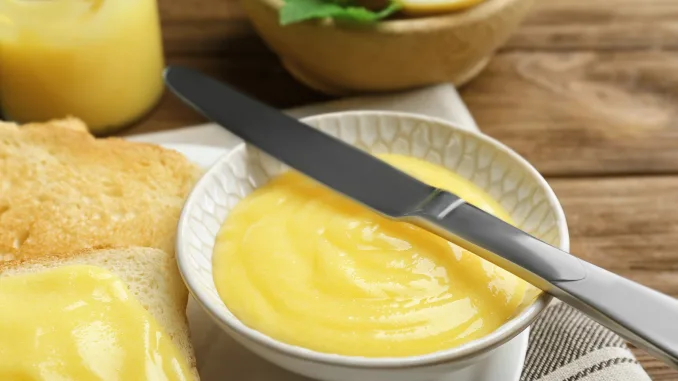 Delicious lemon curd and fresh toasts on wooden table, closeup