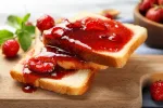 Slices of bread with delicious strawberry jam on board, closeup