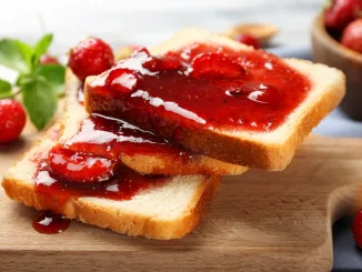 Slices of bread with delicious strawberry jam on board, closeup