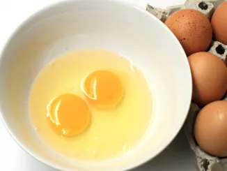 Raw egg cup on white background, egg yolk