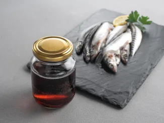 Garum is a fermented fish sauce. Prepared by fermentation from fish, salted garum sauce in a bottle on a gray background. Garum fish sauce made from anchovies on the grey background.