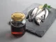 Garum is a fermented fish sauce. Prepared by fermentation from fish, salted garum sauce in a bottle on a gray background. Garum fish sauce made from anchovies on the grey background.