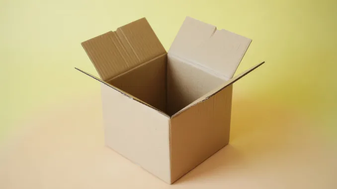 The an open cardboard box with its flaps raised, revealing its empty interior. The box is placed against a smooth, yellowish background. The box is primarily brown with a light-colored interior. The overall composition is simple and minimalistic, highlighting the box's structure and the soft, neutral tones of the background.