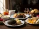 A hearty traditional Scottish meal featuring haggis, neeps (turnips), and tatties (potatoes), served alongside a bowl of soup, oatcakes, cheese, raspberries, and a glass of whisky. The rustic wooden table setting evokes a warm, cultural dining experience. Burns Night.