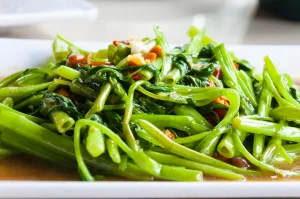 quick-fried water spinach with chili and soy sauce on white plate, Thai food